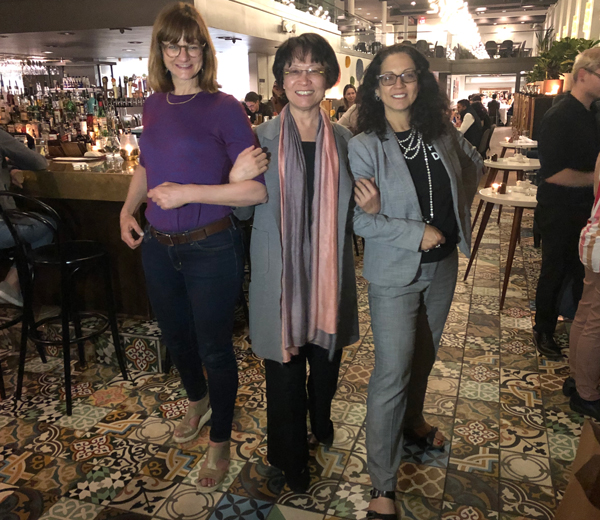 color photo of three women arm-in-arm, in 2019