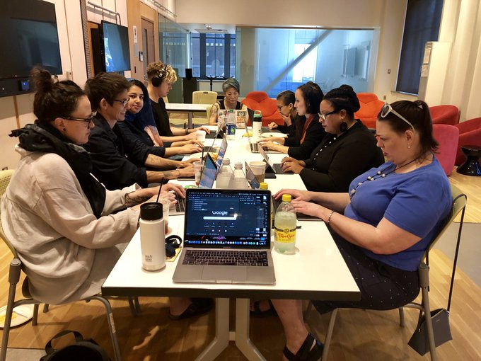 group of scholars working on laptops around a table