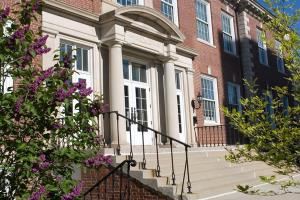 Color photography of lilac blossoms in front of Lane Hall, a UMich Building