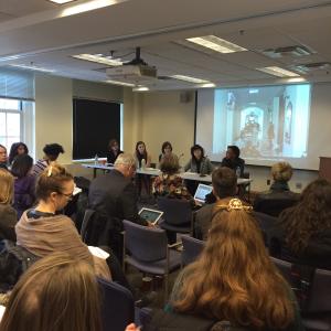 Photo from the event with presenters at a speakers' table and audience members.