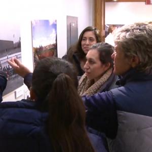 color photo of women looking at exhibit photograph on wall