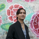 photo of gender nonconforming person in front of painted wall