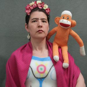 color photo of Heidi Kumao dressed as Frida Kahlo, with a sock monkey on her shoulder