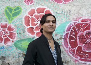 photo of gender nonconforming person in front of painted wall