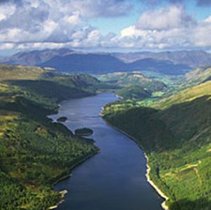 color photo of green mountains with blue river and cloudy sky