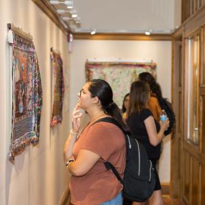 A student looks closely at a digital print on canvas in the Lane Hall exhibit space