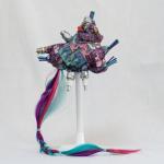 photo of 3D fabric plushy with ribbons, spark plugs, bobby pins and other electronic piece protruding