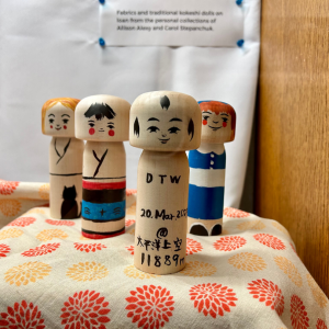 photo of 4 handpainted kokeshi dolls in a display case